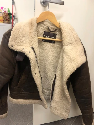 Jacka  - Säljer nu min jätte fina jacka, andvänt några gånger men inget tydligt tecken. En brun mocka/teddyjacka  med fluffigt, beige foder och detaljer som dragkedja och spänne vid kragen. Jackan har en lite  oversized look och är perfekt för kalla dagar . Materialet är mocka på utsidan och mjuk teddy på insidan.