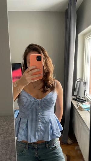 Blå randig korsettopp med knappar - Superfin korsettopp från Zara i blått med smala vita och bruna ränder. Toppen har smala axelband, knappar framtill och en peplum-liknande nederdel som ger en snygg siluett. Ny med prislapp kvar! Storlek 40 men passar bra på mig som vanligtvis har 36-38