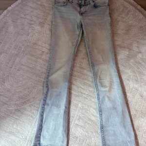Bootcut ljusa jeans från H&M, 164 - Snygga ljusblå bootcut jeans från H&M i storlek 164. Modellen har låg midja och justerbar midja för extra komfort. Jeansen har klassisk femficksdesign och råa kanter vid bensluten för en cool vibe. Perfekta för dig som gillar retrostil och ljusa tvättar.