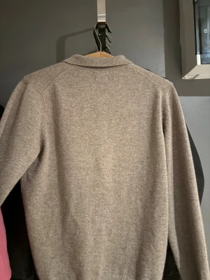Beige pikétröja i ull från Massimo Dutti,kashmir  - Snygg beige pikétröja från Massimo Dutti i kashmir . Tröjan har klassisk krage, två knappar framtill och ribbade muddar vid ärmslut och nederkant. Perfekt för dig som gillar stilrena och tidlösa plagg med en chill vibe.som ny används ändas 2-3 gånger ny pris 2200