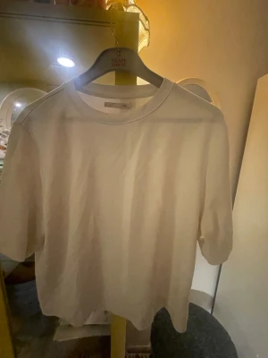 Vit basic t-shirt från 157 - Enkel vit t-shirt från 157 med klassisk rund hals och korta ärmar. Tillverkad i mjuk bomull som känns skön mot huden. Perfekt till jeans eller shorts för en clean och stilren look. Stl S men i en större model.