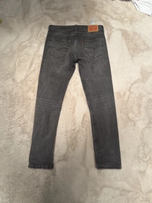 Grå Levi's 502 jeans W32 L34 - Säljer ett par grå Levi's 502 jeans . Jeansen har en snygg tvättad look  Passar perfekt till en avslappnad stil och har den ikoniska Levi's-lappen bak i midjan.