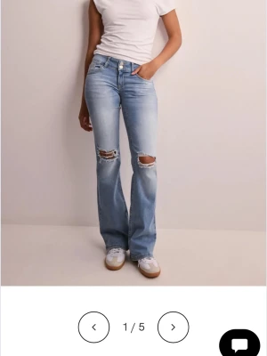 Ljusblå bootcut jeans med slitningar - Säljer ett par ljusblå jeans ifrån Nelly med bootcut passform och slitna hål över knäna, med super fina fickor där bak. Dom är knappt använda och är i fint skick storlek 38