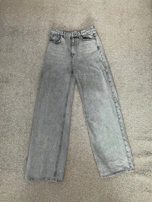 Gråa raka jeans med hög midja - Säljer ett par gråa jeans med rak passform och hög midja. Jeansen har klassisk femficksdesign och är tillverkade i ett slitstarkt jeanstyg. Perfekta för dig som gillar en clean och avslappnad look.