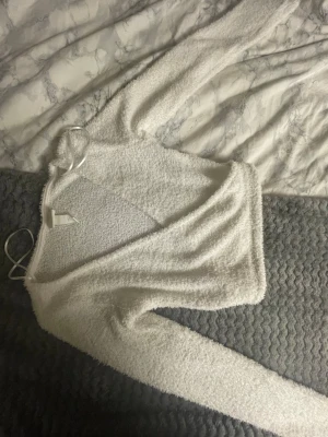 Vitt fluffigt långärmad tröja H&M - Supermjuk och fluffig vit långärmad tröja från H&M. Tröjan har en croppad passform och är tillverkad i ett mysigt, stickat material som känns som fleece. Perfekt för kyliga dagar när du vill vara både bekväm och snygg.