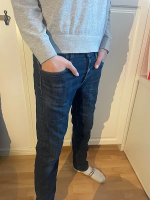 Mörkblå jeans från Lee - Snygga mörkblå jeans från Lee med klassisk femficksdesign och diskreta slitningar. Jeansen har rak passform och normal midja, tillverkade i slitstarkt bomullsmaterial. Perfekta för dig som gillar en enkel och stilren look.