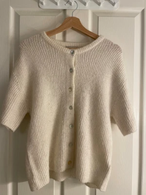 Stickad T-shirt  - Stickad T-shirt med knappar från Gina Tricot. Använd fåtal gånger så i jättefint skick.