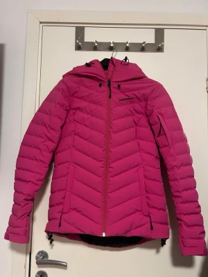Rosa pufferjacka Peak Performance  - Säljer en riktigt snygg rosa pufferjacka från Peak Performance i storlek S. Jackan har huva, dragkedja framtill och två sidofickor med dragkedja. Snyggt mönstrad med horisontella och snedställda sömmar för extra stilpoäng. Aldrig använd så den är i mycket bra skick. Perfekt för kalla dagar! Pris kan diskuteras vid snabb affär