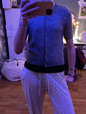 Grå kofta med kort ärm från H&M - Mysig grå kofta från H&M med korta ärmar och rund hals. Koftan har gulfärgade knappar och lite tajtare i ärmarna.