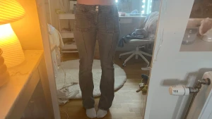 Grå bootcut jeans - Säljer ett par gråa jeans med bootcut-modell och stora framfickor. Byxorna är lowwaist med och markerade sömmar längs benen.