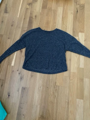 Mörkgrå ribbad tröja från Pigalle - Mysig mörkgrå långärmad tröja från Pigalle i storlek S. Tröjan har ett ribbat mönster och är tillverkad i ett mjukt stickat material. Perfekt för kyligare dagar och enkel att matcha med jeans eller kjol.