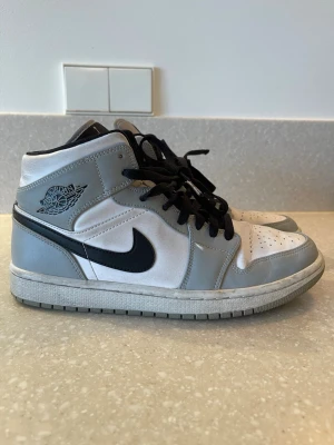 Nike Air Jordan 1 Mid grå/vit - Sneakers Nike Air Jordan 1 Mid. Grå/vit med svarta detaljer. Storlek 41 (UK7, US8). Endast använda ett fåtal gånger. 