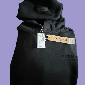 Svart Essentials Fear of God hoodie L -  VERIFIED FRÅN VINTED Svart hoodie från Essentials Fear of God i storlek L. Klassisk oversized passform med stor huva och känguruficka ej äkta . Broderad logga på bröstet och ryggen. Mjuk bomullsblandning, perfekt   för en chill och stilren look. Vet inte om det är äkta köp på egen risk