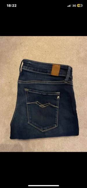 Mörkblå Replay jeans  - Snygga mörkblå jeans från Replay, Klassisk femficksdesign med kontraststickningar och läderpatch bak i midjan. Jeansen har en rak passform och är tillverkade i slitstarkt denimtyg med diskret tvättad look. Storlek 32