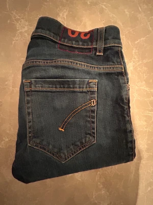 Dondup George  - Snygga blå jeansbyxor med klassisk femficksdesign och raka ben. Jeansen har kontrastsömmar och en normal passform som funkar till de flesta stilar. Materialet är slitstarkt jeans och färgen är en klassisk blå denim.