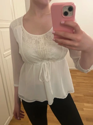 Fin vit blus från Vero Moda - Smickrande blus med resor och knytning i midjan och fina detaljer framtill.