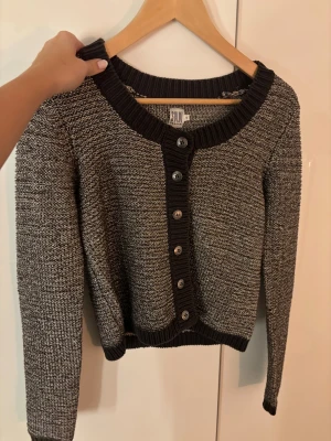 Glittrig kofta från Saint Tropez - Snygg glittrig kofta från Saint Tropez i storlek S. Koftan är stickad i brun/grå och silver, har långa ärmar och knappar framtill. 