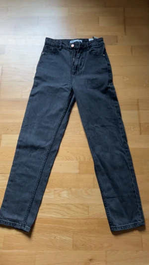 Svarta straight jeans från Zara - Säljer ett par svarta jeans från Zara i storlek 32. Modellen har klassisk femficksdesign, raka ben och hög midja. Jeansen är tillverkade i ett slitstarkt bomullsmaterial och har knapp- och dragkedjestängning framtill. Frakt pris diskuteras! 