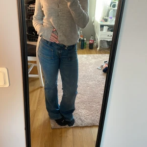 Blå bootcut jeans från 157 Paris XS - Snygga blå jeans från 157 Paris i storlek XS med kort längd. Modellen har bootcut-ben, klassiska fickor fram och bak samt normal passform. Jeansen är tillverkade i jeansmaterial och har en cool, avslappnad vibe.