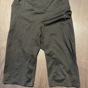 Svarta cykelshorts i stretch - Svarta cykelshorts med hög midja och tight passform. Tillverkade i mjukt och stretchigt syntetmaterial som sitter skönt mot kroppen. Perfekta för träning eller chill dagar. Klassisk design utan synliga detaljer eller mönster.