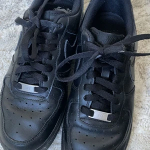 Svarta Nike Air Force 1 sneakers - Helsvarta Nike Air Force 1 sneakers i skinn med svart sula och svarta skosnören. 