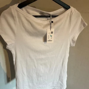 Vit ribbad topp från lager 157 - Säljer en enkel och fräsch vit ribbad topp , Toppen har korta ärmar, rund halsringning och är tillverkad i mjuk bomull. Perfekt att matcha med jeans eller kjol för en clean look.