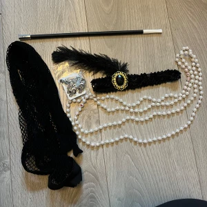 Gatsby halloweenkostym - Snygg gatsbykostym, passar perfekt nu till halloween 🤍 använde den förra året och den är i bra skick, endast pärlhalsbandet har lite fakeblod på sig men inget som syns speciellt mycket. Det som kommer med är ett långt pärlhalsband, elastiskt diadem, pinne, örhängen (oanvända) samt nätstrumpbyxor (endast testade). Snygga tillbehör som jag valde att ha med en svart klänning o klackar förra halloween då jag var utklädd till Daisy från the great Gatsby.