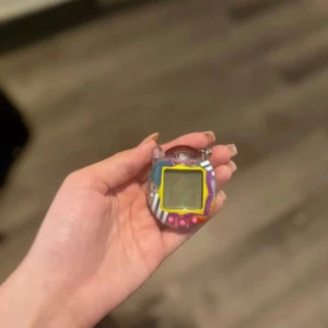 Tamagotchi V3 - Klassisk Tamagotchi digitalt husdjur från Bandai. Färgglad design med tre knappar och tydlig skärm. Produkten är i gott skick med minimalt slitage. Perfekt för samlare eller nostalgiker som vill återuppleva 90-talets digitala leksak.