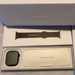 Apple Watch Series 10 Jet Black 46mm - Apple Watch Series 10 i Jet Black med 46mm boett och svart sportband. Klockan har en modern, fyrkantig design och levereras i originalförpackning. Perfekt för dig som vill ha koll på både träning och notiser direkt på handleden.