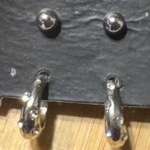 Silvriga örhängen med stenar - Säljer ett par coola silvriga örhängen i rund form med små gnistrande stenar. De har en chunky design och är perfekta för att ge din look lite extra edge. Passar dig som gillar statement-smycken och vill sticka ut.