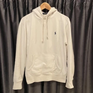 Polo Ralph lauren hoodie  - Raffe hoodie - vit - skick 8/10, själva hoodien är i suveränt skick, ända defekterna är ett par små fläckar här o där, (ex: bild 4 & bild 5), därav priset - Fläckarna kanske går bort i tvättmaskinen, har ej prövat själv - storlek S, passar S, jag är 177 och den passar perfekt - pris kan diskuteras! 