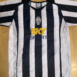 Juventus Ibrahimovic 9 matchtröja - Juventus fotbollströja med klassiska svarta och vita ränder, officiellt klubbmärke och sponsortryck på bröstet. På ryggen står Ibrahimovic och nummer 9 i gult. Tröjan är kortärmad och tillverkad i lätt, ventilerande polyester.