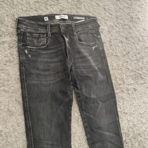 Replay svarta slim jeans - Snygga svarta Replay jeans med slitna detaljer och tvättad look. Modellen är slim med klassiska fem fickor och läderpatch bak i midjan. Jeansen har en mörkgrå ton och är tillverkade i stretchig bomullsdenim för en bekväm passform. Dom är aged 5 år och har inga defekter. Pris inte hugget i sten