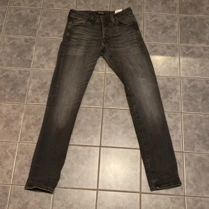 Svarta skinny jeans från Jack & Jones - Snygga svarta skinny jeans från Jack & Jones med diskret tvättad look. Klassisk femficksmodell med dragkedja och knapp. Jeansen har smal passform och är tillverkade i stretchigt jeanstyg för extra komfort.