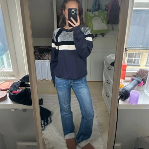 Mörkblå glittrig tröja från Sandro - Säljer en snygg och unik mörkblå tröja från Sandro Paris med glittriga silverpartier och vit rand över bröstet. Tröjan är väldigt cool och perfekt för dig som vill sticka ut lite extra.