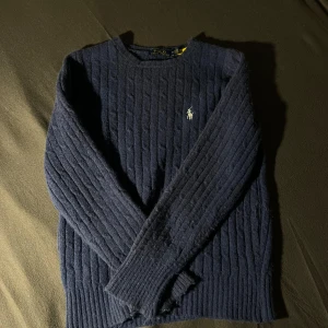 Mörkblå kabelstickad tröja Polo Ralph Lauren - Kabelstickad mörkblå tröja från Polo Ralph Lauren. Bra skick med inga defekter. Hör av dig vid funderingar☺️