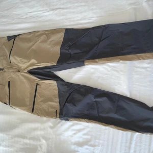 Beige och svarta täckbyxor Haglöfs S - Säljer ett par outdoorbyxor från Haglöfs i storlek S. tunna i matrial men är stretchiga