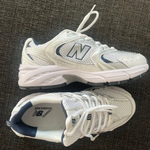 Vita New Balance 530 sneakers - Säljer ett par helt nya fräscha New Balance 530 sneakers i storlek 38.5. Skorna är vita med detaljer i silver och marinblått. Skorna har mesh och syntetmaterial, klassisk snörning och en chunky sula som ger skön komfort. Perfekta för dig som gillar sportig och clean stil. Helt oanvända, endast testade. Kommer i originalkartong🌸