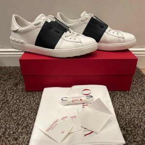 Valentino Garavani Open sneakers vit/marin - Snygga Valentino Garavani Open sneakers i vitt skinn med bred marinblå rand över mitten. Klassisk rund tå, vita snören och coola nitar baktill på sulan. Kommer med originalkartong, extra skosnören, kvitto och dustbag. Knappt använda! Frakt ingår EJ💕