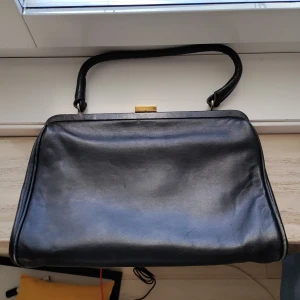 Svart läderväska - Snygg svart läderväska med ett stort fack och 3 mindre innerfack varav ett har dragkedja (se bild 2). Väskans storlek är 31x21x6 cm. På märkesettoketten står det "Väskindustri Göteborg Orginal modell". Väskan är lite sliten på vissa av kanterna (se bild 4-5). 