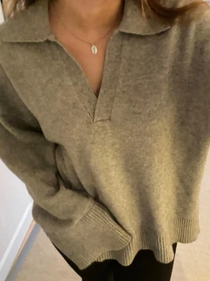 Grå stickad tröja från BikBok - Mysig grå stickad tröja från BikBok med krage och v-ringad öppning framtill. Tröjan har lång ärm och ribbade muddar vid ärmslut och nederkant. Perfekt för lager på lager under höst och vinter. Använd fåtal gånger 