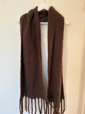 Varm fluffig brun stickad halsduk  - Varm och fluffig stickad halsduk i brun färg 🤎 Supermjuk och mysig – perfekt för kalla höst- och vinterdagar. Passar till allt och ger en stilren men cozy look. 