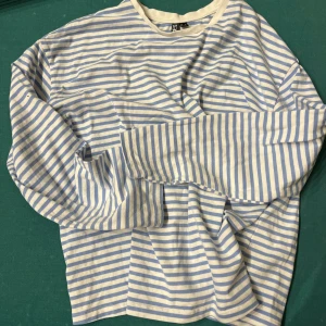 Randig långärmad tröja från PIECES - Säljer en fräsch långärmad tröja från PIECES i vitt och ljusblått med klassiskt randigt mönster. Tröjan har en relaxed fit och är gjord i mjuk bomull, perfekt för vår och sommar. Enkel rund halsringning och tidlös design.