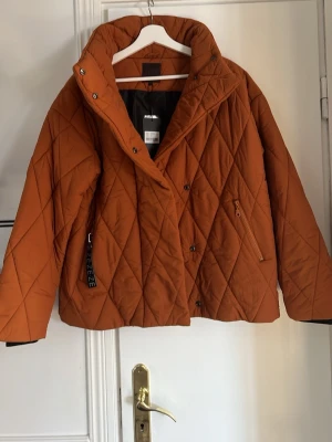Quiltad brun pufferjacka från Ze-Ze - Säljer en brun quiltad pufferjacka från Ze-Ze i storlek S. Jackan har hög krage, dragkedja och knappar framtill samt snedställda fickor med dragkedja. Ribbstickade muddar vid ärmsluten för extra komfort. Perfekt för kyliga dagar!