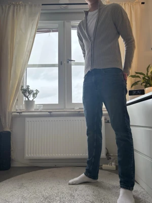 Beige ribbad kofta med dragkedja - Säljer en stilren beige  ribbad kofta med dragkedja och hög krage. Koftan är långärmad och har en clean look som passar perfekt till jeans eller chinos. Materialet känns mjukt och är troligtvis bomull eller en bomullsblandning.