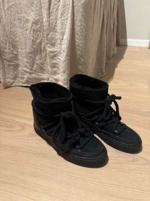 Svarta boots från Inuikii, storlek 38 - Säljer ett par svarta boots från Inuikii i storlek 38. I väldigt bra skick då de endast är använda någon gång. Skorna har en rund tå, platt sula och grova snören. Utsidan är i mocka och skinn, med mjukt foder på insidan som gör dem extra sköna. Perfekta för kalla dagar men samtidigt fina.💗 Nypris:2999kr