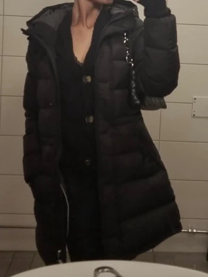 Svart lång pufferjacka med huva - Säljer en svart pufferjacka med huva och dragkedja. 