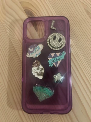 Dreamland mobilskal IPhone 12 - Lila mobilskal från Dreamland som passar IPhone 12. Inklusive 7 dekaler. 