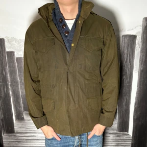 Olivgrön parkajacka från Whyred - Säljer en olivgrön parkajacka från Whyred med fyra stora fickor framtill, axelklaffar och snygga guldfärgade knappar. Jackan har dragkedja och tryckknappar, rak passform och är tillverkad i ett slitstarkt bomullstyg. Perfekt för dig som gillar stilren och funktionell design.