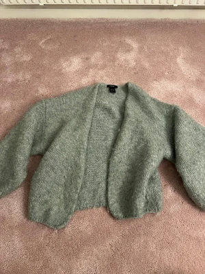 Grå stickad kofta från Lindex - Mysig grå stickad kofta från Lindex i storlek XS/S. Koftan har en loose passform  och öppen front, perfekt att slänga på sig över en t-shirt eller topp. Den är supermjuk och passar för kyliga och somriga dagar.